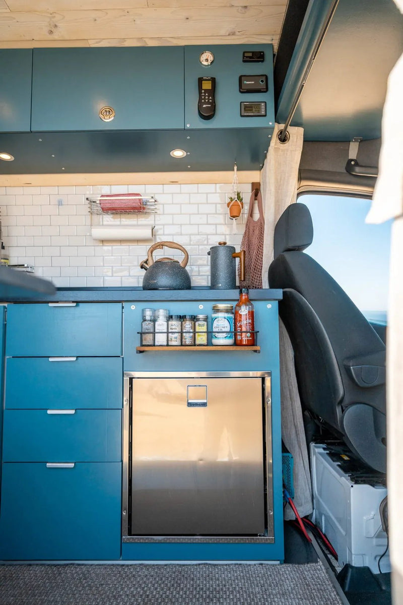  and bright interior. Ideal for mobile adventures.|Explore this compact RV rental! A bright camper van interior features a blue kitchen with sink — photo 3