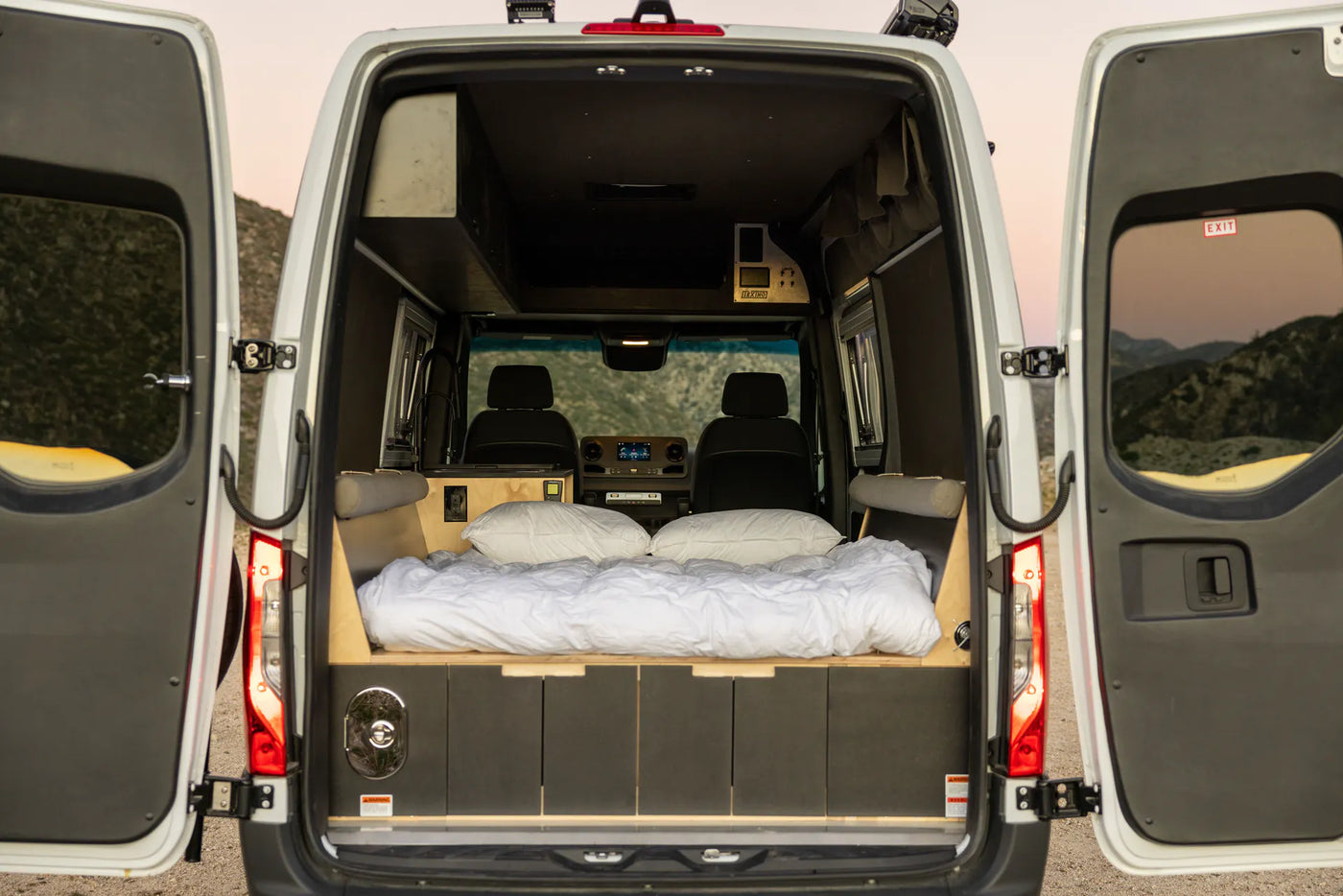  parked by a red curb. Ideal for your next RV rental.|Inside an RV rental: A man and dog enjoy beach views. Overhead storage & kitchen are visible — photo 3