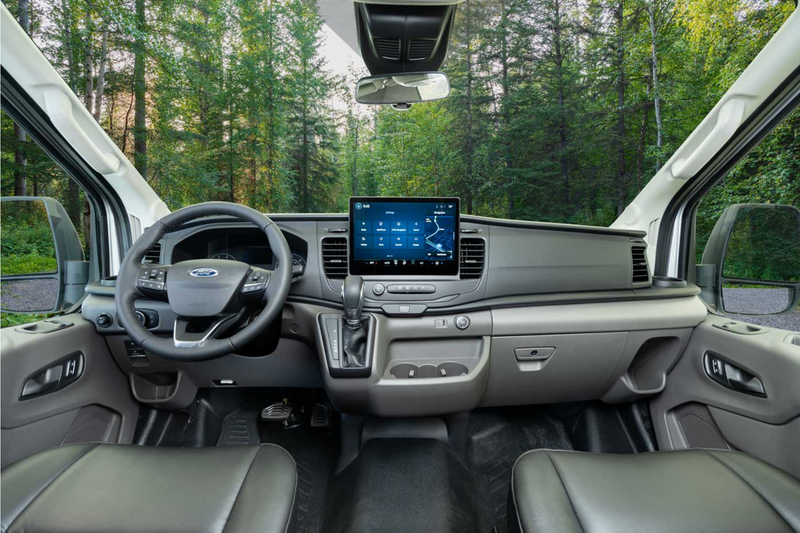 Spacious Ford RV rental interior with modern dashboard, large touchscreen display, and a forest view. — photo 12