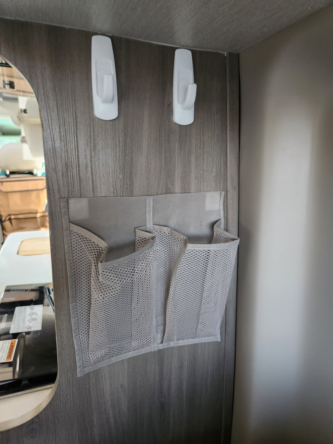 RV rental interior showing a gray fabric mesh organizer with three pockets and white Command Hooks for space-saving storage.