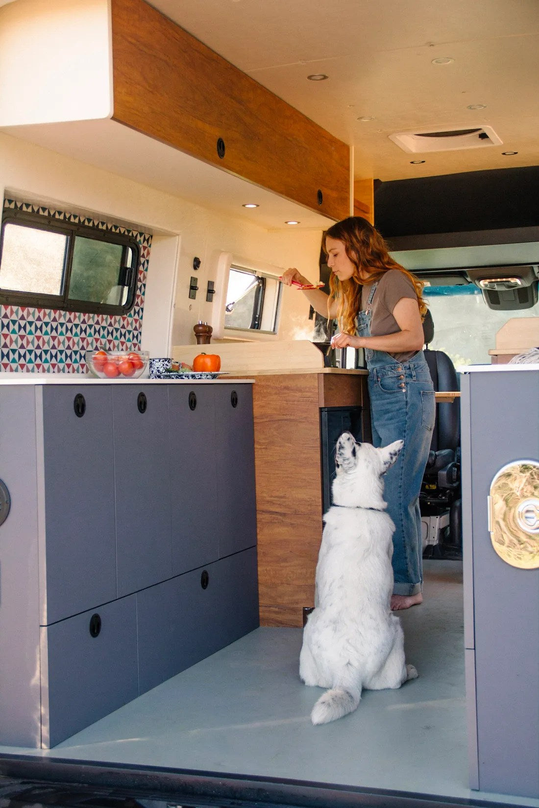 A woman cooks in a stylish rv rental van kitchen