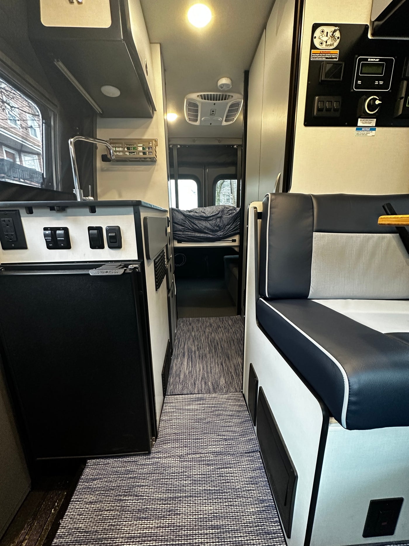 Step inside this RV rental's compact interior, featuring a kitchen with a sink, comfortable seating, and a bed in the rear. — photo 14