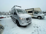 Silver Mercedes Sprinter camper van & Class C RV covered in fresh snow at an RV rental lot. Perfect for winter adventures!