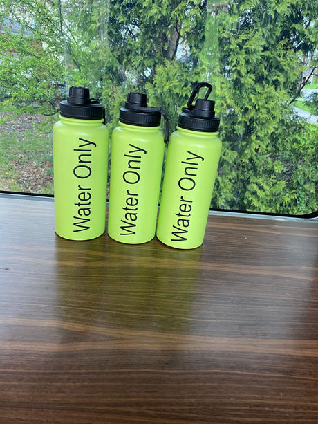 Three bright green "Water Only" bottles on a wooden table in an RV rental, with green trees visible outside.