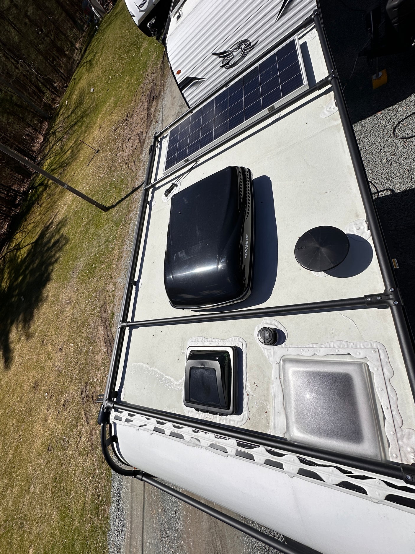 Top-down view of an RV rental roof featuring solar panels, a Dometic AC unit, vents, and a roof access rack.