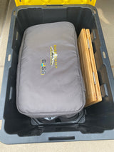 RV rental gear: a grey BOSS Base Camp carrying case and a folded bamboo item neatly stored in a black bin.