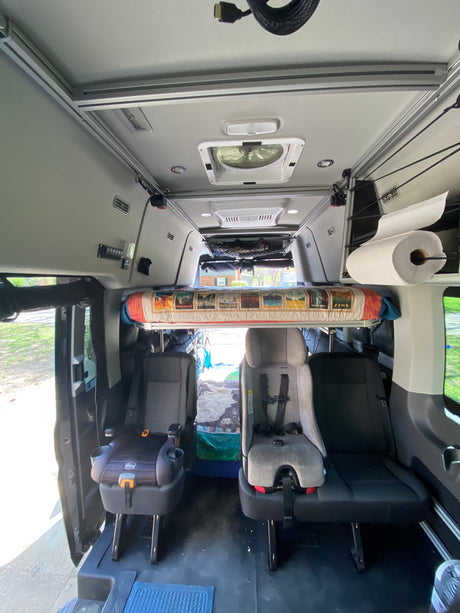 RV rental interior features overhead bunk, child seats, ceiling fan, and storage for family trips.