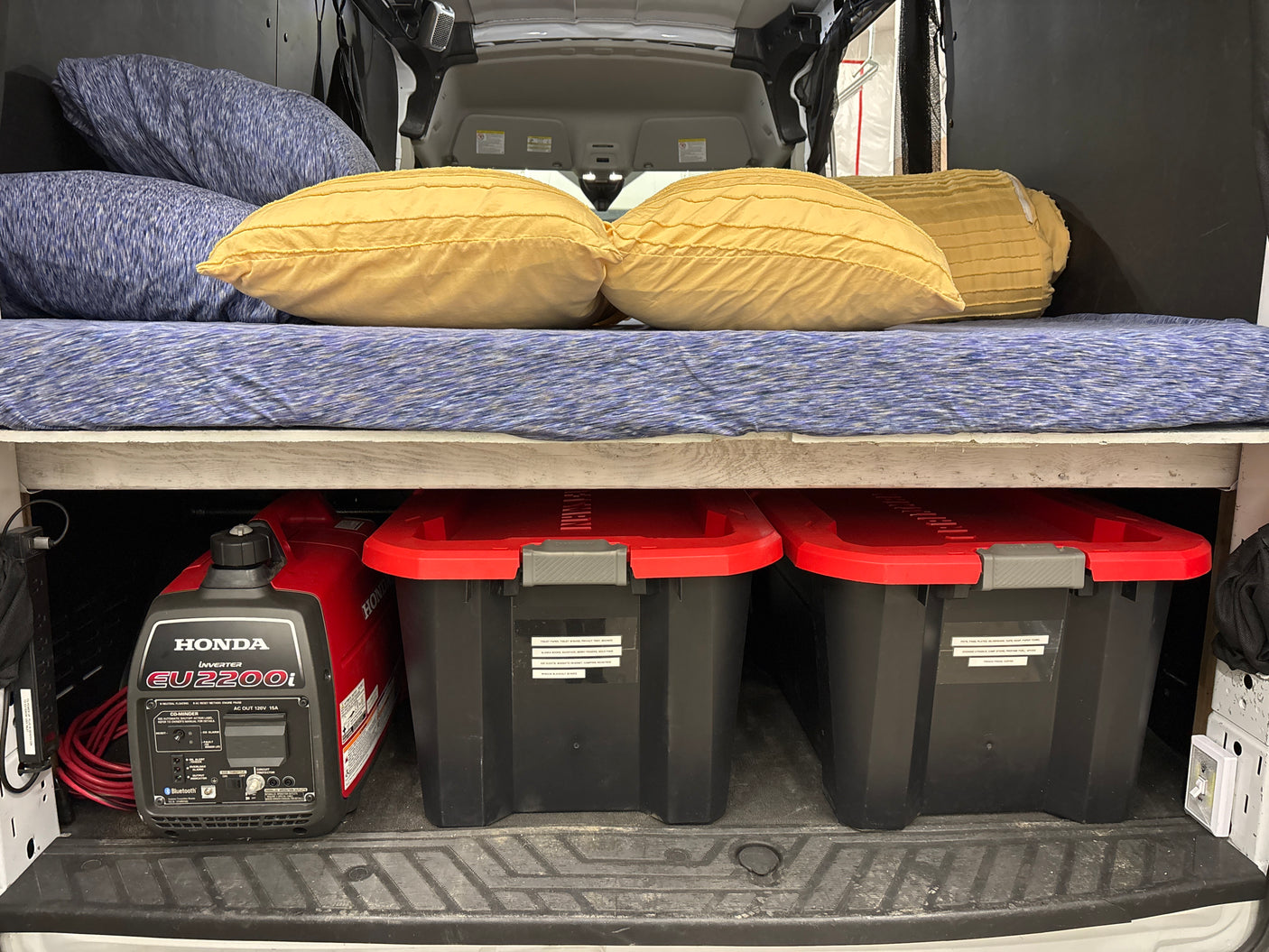 RV rental: Honda EU2200i generator and organized bins under a comfy bed, ideal for van life camping.