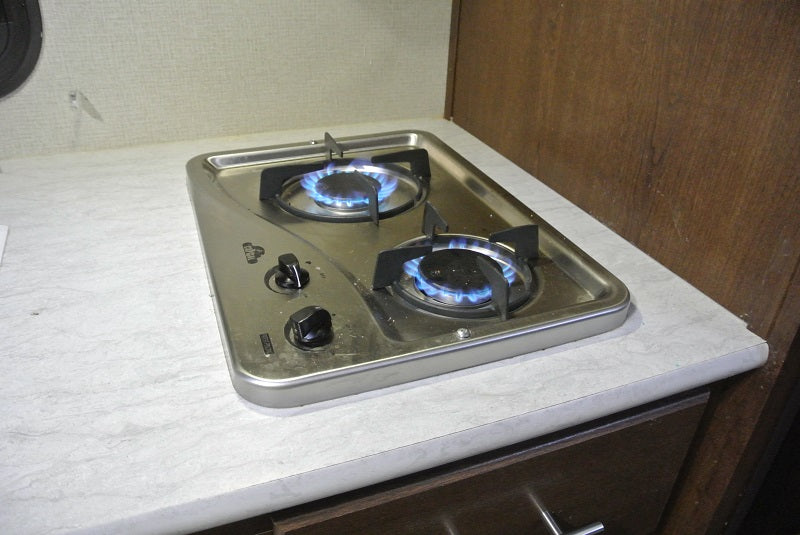 Two-burner gas stove with blue flames in an RV rental. Perfect for compact kitchen cooking on the go.