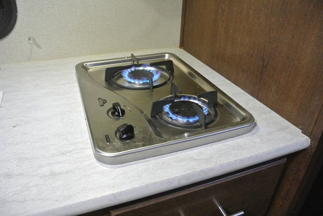 Two-burner gas stove with blue flames in an RV rental. Perfect for compact kitchen cooking on the go.