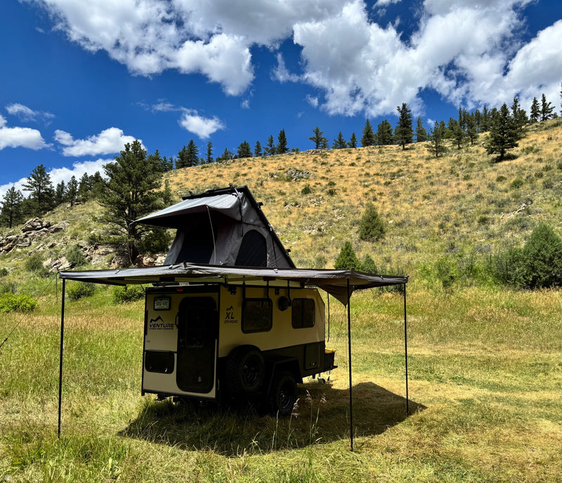 RV rental: An off-road camper with a rooftop tent and awning set up in a lush, grassy field under blue skies. — photo 2