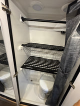 Compact RV rental wet bath featuring a toilet, shower area, storage shelves, and a privacy curtain.