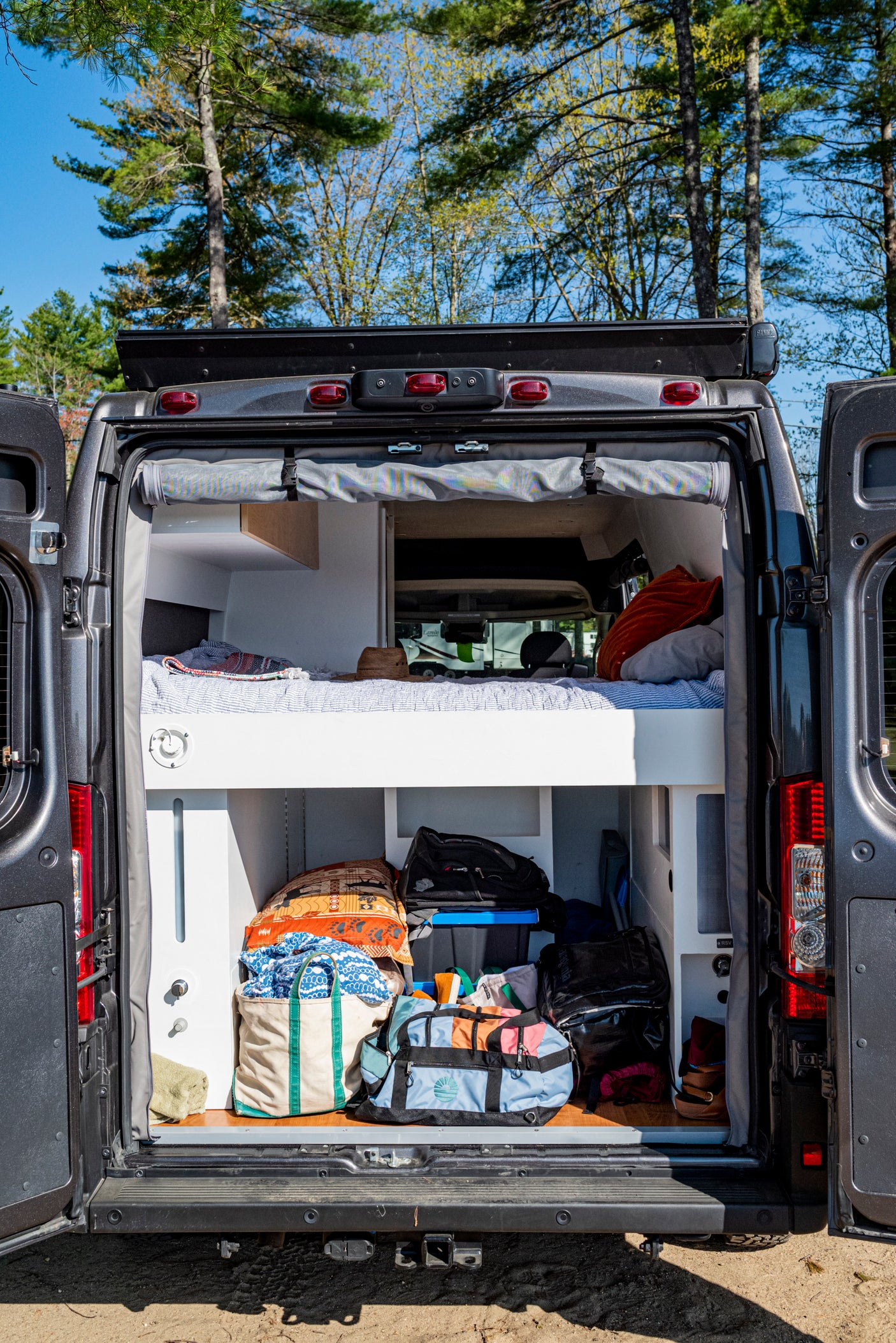 This RV rental offers comfort & utility: a camper van's interior with a cozy bed and smart storage for your adventures.