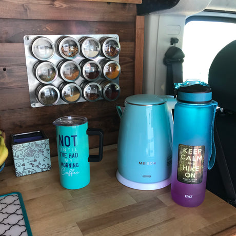 RV rental: a vibrant collection of travel essentials – kettle, water bottle, coffee mug, and magnetic spices on wood.