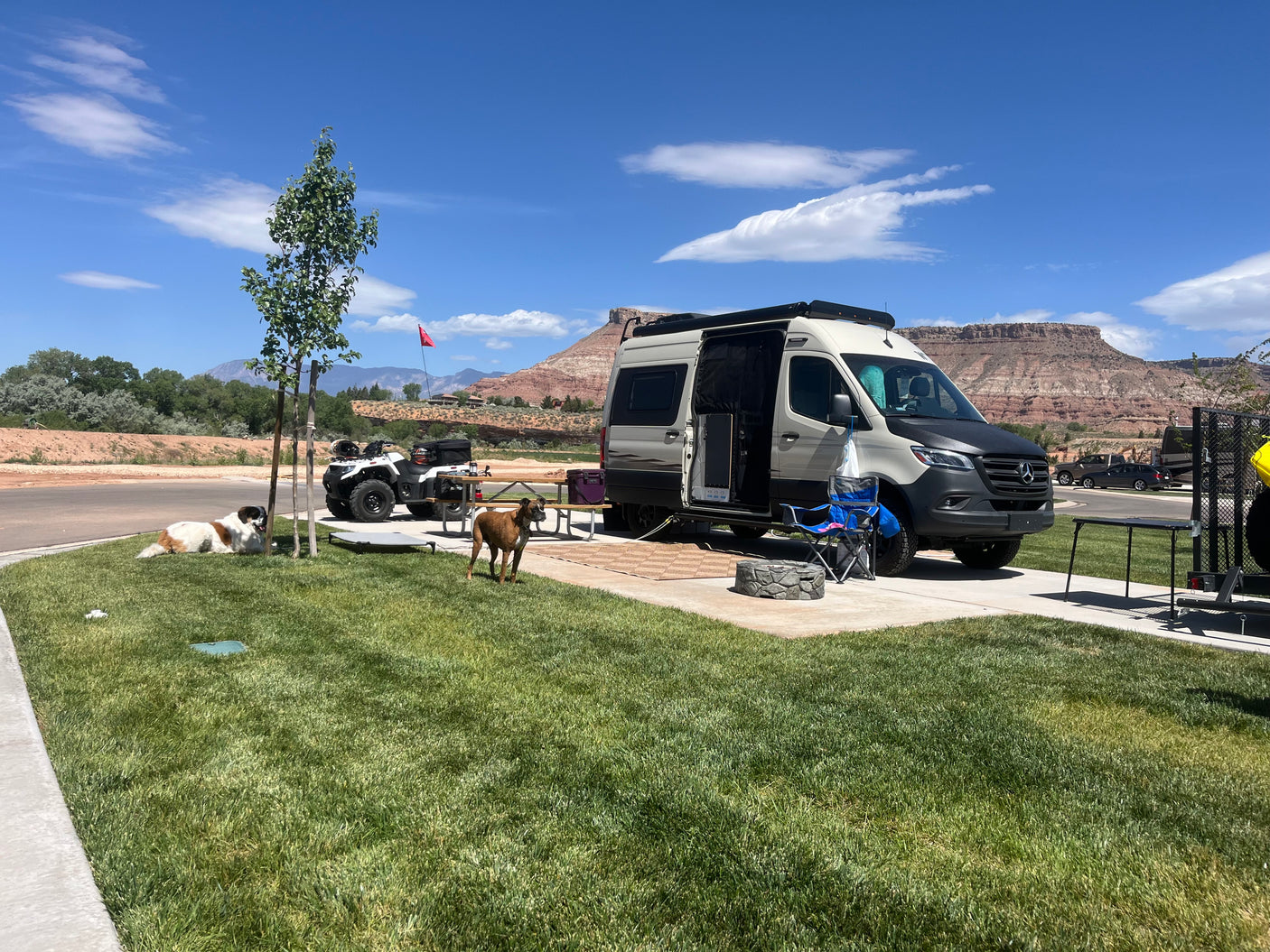 This RV rental is set up for a fun camping trip with dogs and an ATV against scenic red rock mountains.