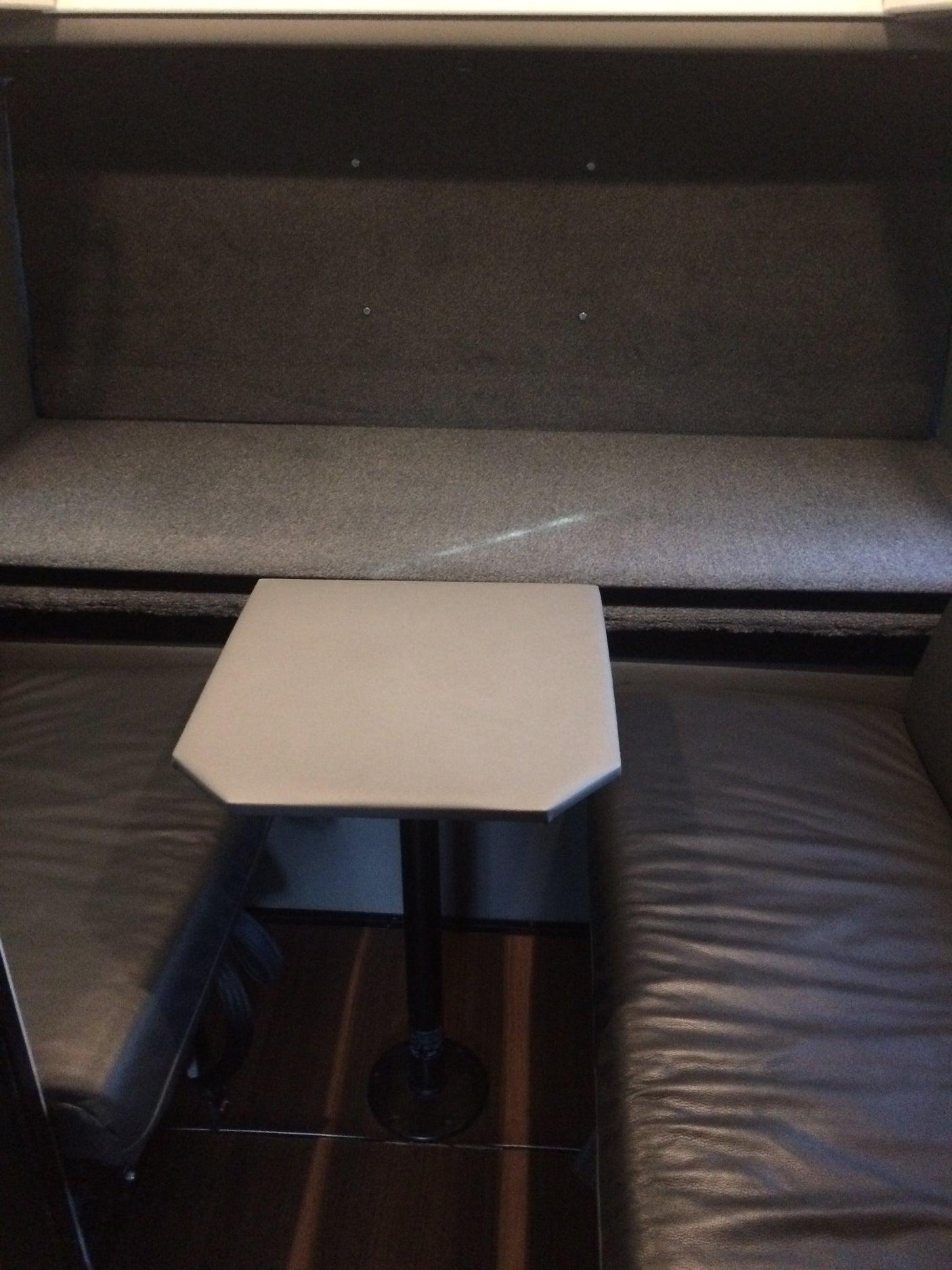 Cozy RV rental dining booth: featuring a grey fabric backrest, dark leather seats, and a unique hexagonal table.