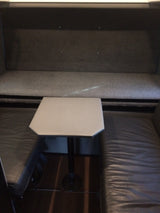 Cozy RV rental dining booth: featuring a grey fabric backrest, dark leather seats, and a unique hexagonal table.