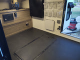 RV rental interior: patterned floor, wall-mounted organizer & folding table. Practical space for travelers.