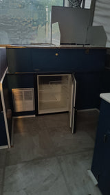 Inside this RV rental: A compact kitchen area featuring a top-mounted stove, open mini-fridge, and vent unit.