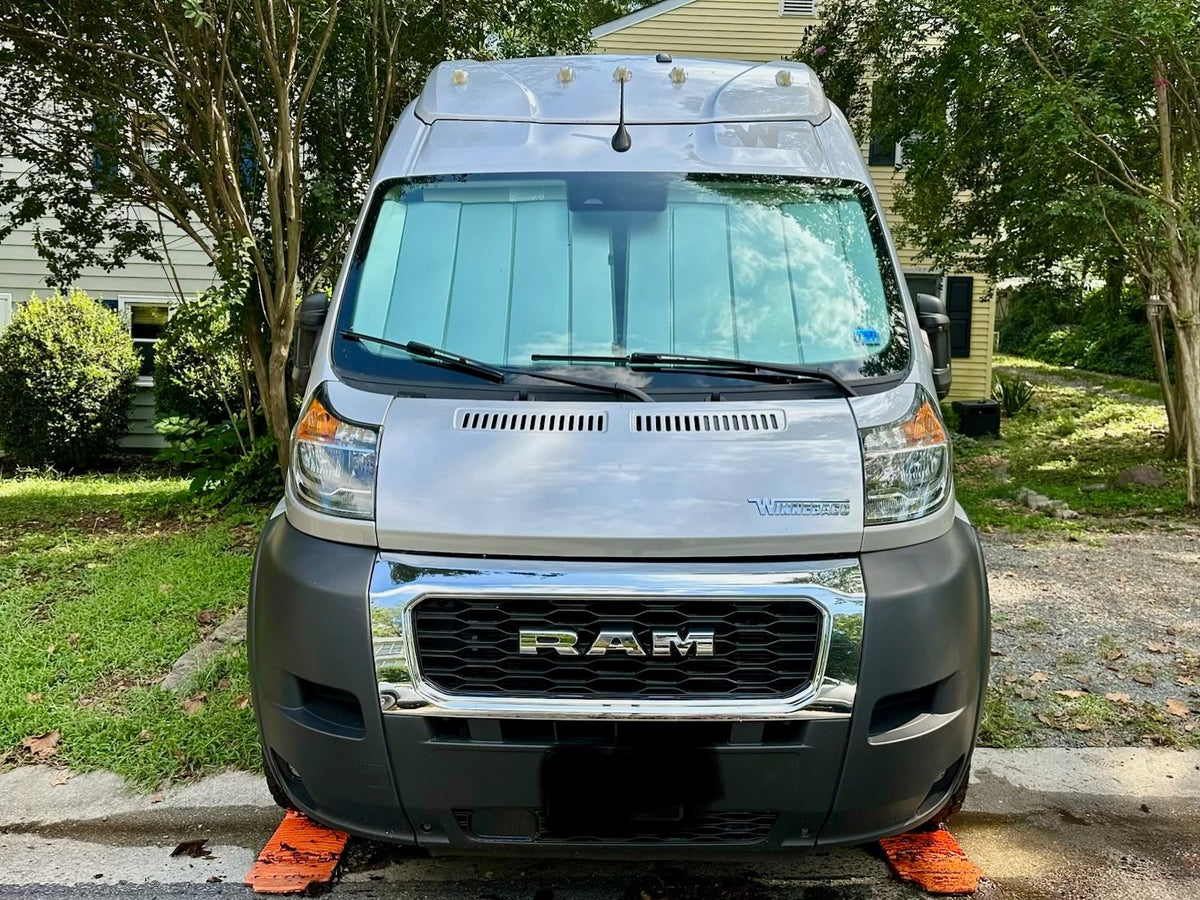  parked on a driveway with a wooded background.|A silver Winnebago Solis camper van (RV rental) parked outdoors under trees — photo 3