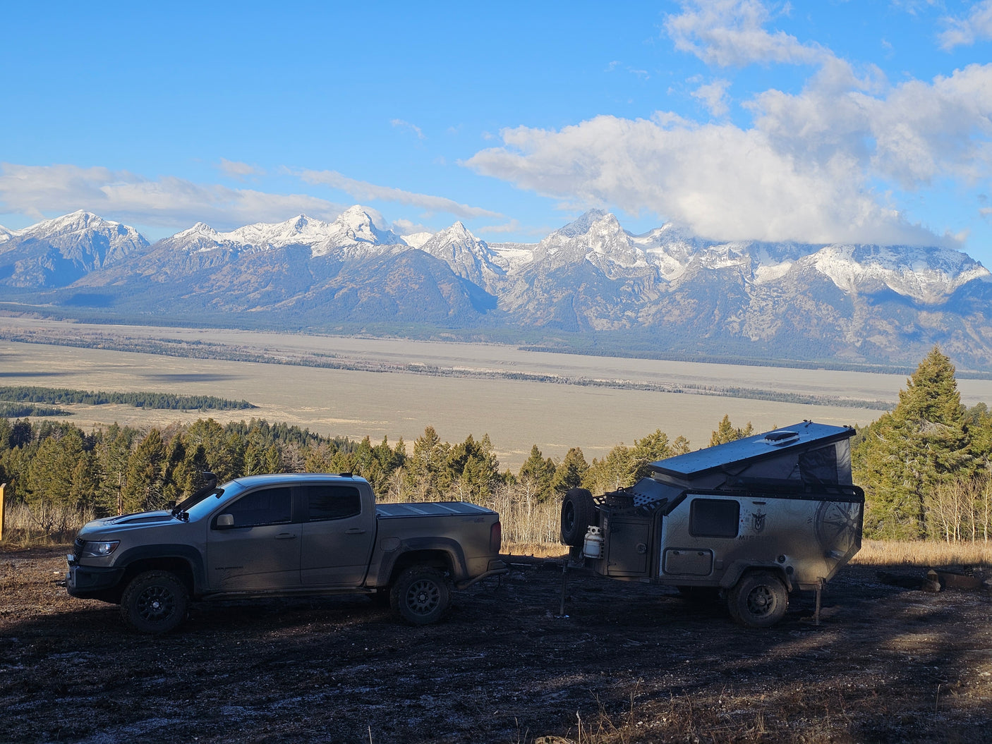 Truck and RV rental camper parked with the stunning Grand Tetons as a backdrop for outdoor adventure.