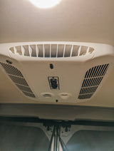White overhead RV rental AC unit with vents & control knobs for fan/cool. Essential for comfortable travel.