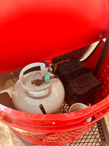 Propane tank, regulator, and battery box within an **rv rental**'s portable fire pit setup. Essential camping gear.
