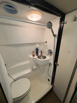 Compact RV rental bathroom with toilet, sink, and shower—perfect for on-the-go comfort and utility.