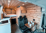Explore this modern RV rental interior featuring a bed, kitchenette with sink & cooktop, and dining area. Comfort on the road!