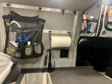 RV rental interior: sink, black faucet, mesh organizers, and charging station against gray walls for compact living.