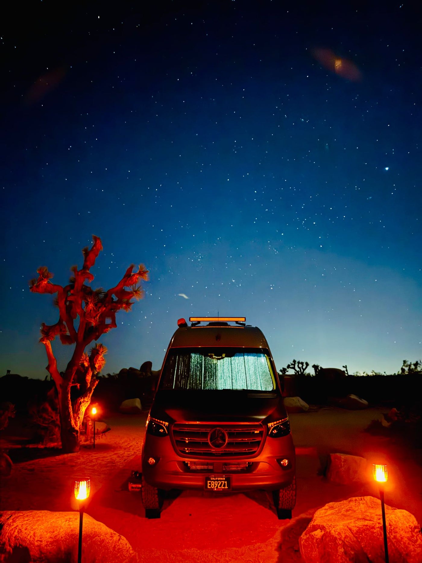  showing a cozy outdoor living area with chairs and ambient lighting.|Stargazing adventure with an RV rental: a van under a brilliant starry desert sky — photo 2