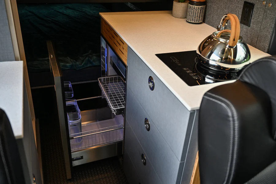 Compact RV rental kitchen with an induction cooktop, pull-out fridge, and smart storage solutions for mobile living.