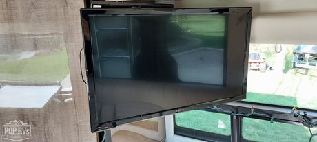 Enjoy entertainment in your RV rental! View of a TV mounted in the living space with outdoor scenery visible through windows.