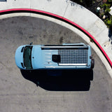 Aerial view: light blue camper van with solar panels, parked by a red curb. Ideal for your next RV rental.