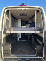 RV rental: Spacious camper van interior with an elevated bed, large storage area, and modern amenities.