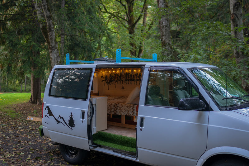 Cozy custom camper van, perfect for your next rv rental adventure. Features a comfy bed, string lights, and nature decals. — photo 6