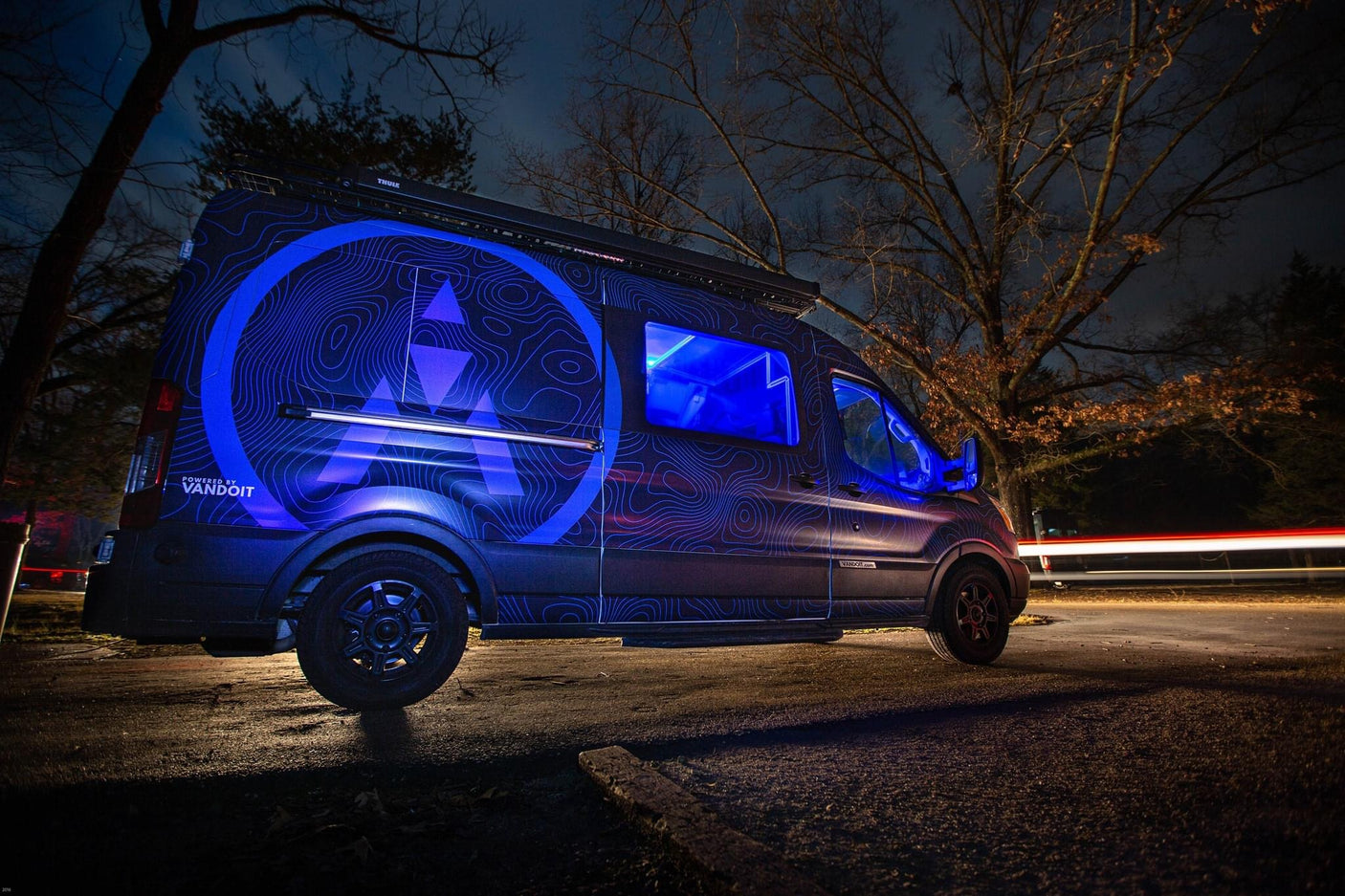 Custom blue-lit camper van with topo map design by Vandoit, ideal for your next RV rental adventure at night.