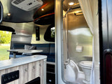 Compact and functional RV rental interior featuring a dinette with views outside and a self-contained bathroom with shower and toilet.