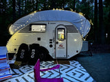 This inviting Little Guy teardrop RV rental shines under string lights at night, creating a perfect camping oasis.