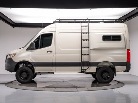 Side view of a tan Mercedes Sprinter rv rental camper van with a roof rack and ladder, on a studio turntable.