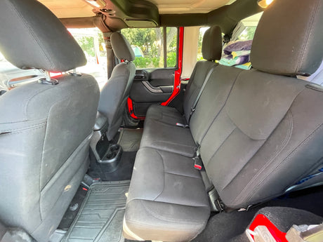 Rear view of an **RV rental** Jeep interior, showing comfortable black fabric seats and durable floor mats. Ideal for adventures.
