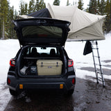 Subaru with rooftop tent deployed, YETI cooler, & Anker power station for snowy car camping. RV rental alternative.