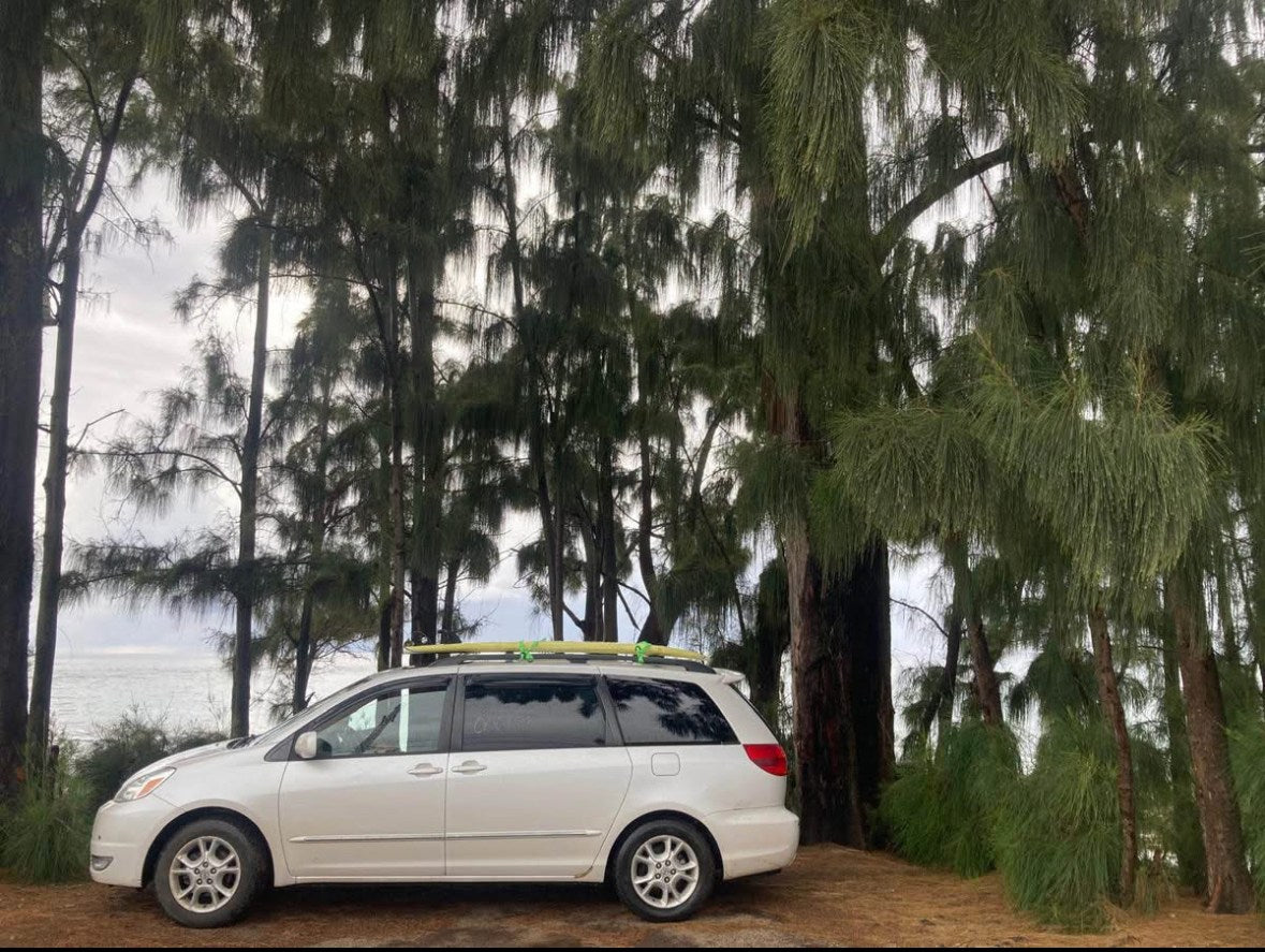 White minivan with surfboard by ocean & pines. Explore like an RV rental adventure!|Cozy RV rental interior with a dark quilted bed