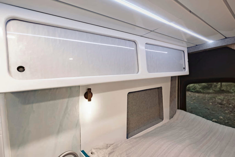  and a practical fold-down table for travel.|Modern RV rental interior with a compact kitchen — photo 9
