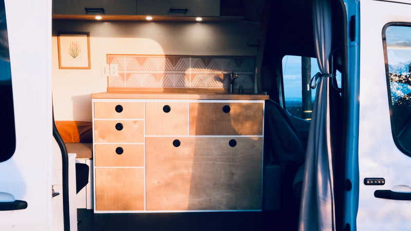  showcases its custom wood interior with an open side door on a scenic mountain road.|Inside this cozy RV rental: quilted front seats — photo 3