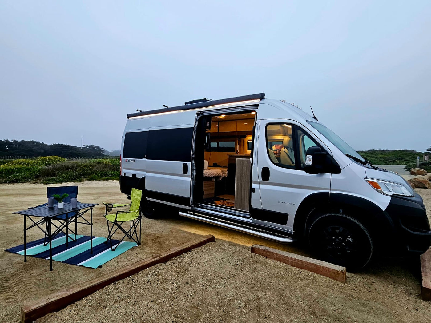  overlooking Morro Rock and the ocean.|A white RV rental van and SUV parked on a misty — photo 3