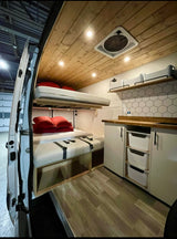 Modern rv rental interior featuring bunk beds, a wood ceiling with fan, organized kitchen, and ample storage.
