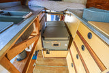 Compact RV rental interior with kitchen sink, bed, and a central pull-out fridge for convenient travel.