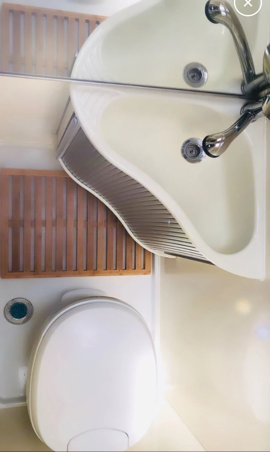 Compact RV rental bathroom with corner sink, mirror, toilet, and wooden floor mat for a cozy travel experience. — photo 4