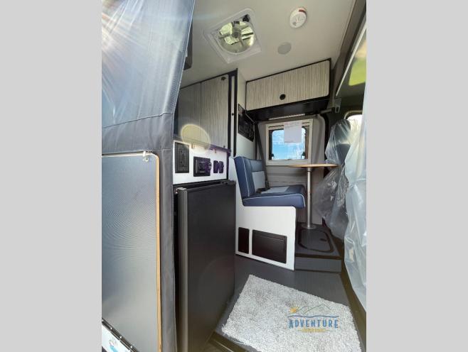  and outdoor setup at an RV park.|Open rear doors of a gray rv rental camper van reveal a spacious interior with modular seating and a clean gray floor — photo 2